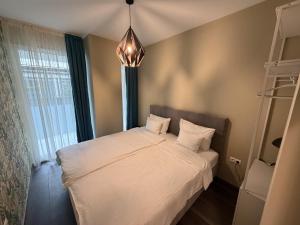 ein Schlafzimmer mit einem Bett mit weißen Laken und einem Kronleuchter in der Unterkunft Noir Hotel in Szeged + 118 Fotos