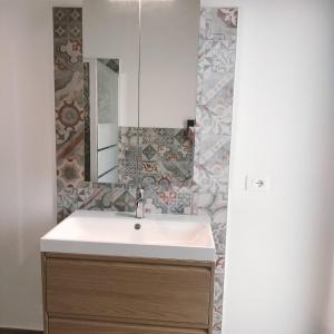 a bathroom with a sink and a mirror at New semi-detached two-room apartment in Monserrato