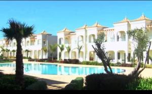 a large white mansion with a swimming pool at Mozona beach 2 in Sidi Rahal