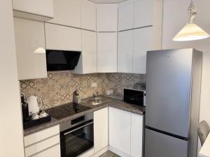 eine weiße Küche mit Spüle und Kühlschrank in der Unterkunft Noir Hotel in Szeged