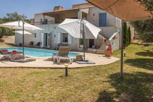 a pool with two chairs and umbrellas next to a house at Villa Bollaccia - piscine privée proche de la mer in Aregno