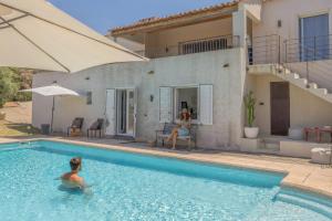 a woman in a swimming pool next to a house at Villa Bollaccia - piscine privée proche de la mer in Aregno