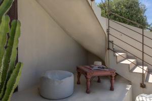 a table and a stool next to a stairs with a cactus at Villa Bollaccia - piscine privée proche de la mer in Aregno