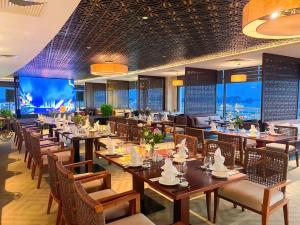 a restaurant with tables and chairs and a large screen at Sai Gon Ha Long Hotel in Ha Long