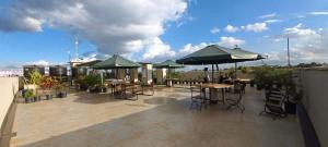 a patio with tables and umbrellas on a rooftop at Reinastays in Kiambu