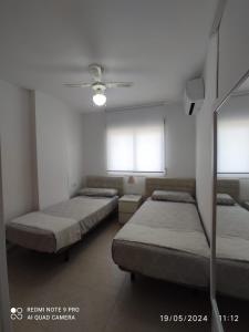 two beds in a room with two windows at Apartamento Piles playa in Piles +6 photos