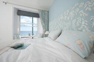 a bedroom with a large white bed with a window at Sophia's in Penzance