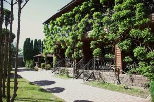 a person standing next to a building with trees at Hotel-complex Mizh Triokh Ozer in Svityazʼ