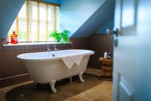 a white bath tub in a bathroom with a window at Plough Inn in Lupton +24 photos