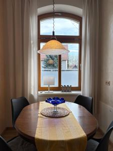 a dining room table with a lamp and a window at Ferienwohnungen Landeskrone Dresden in Dresden