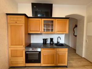 a kitchen with wooden cabinets and a black stove at Ferienwohnungen Landeskrone Dresden in Dresden