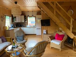 a living room with chairs and a table and a kitchen at Domek u Ewy in Rydzewo +11 photos
