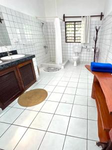 a white tiled bathroom with a sink and a toilet at Beach House - private room in Diani Beach