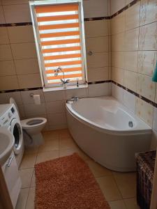 a bathroom with a tub and a toilet and a window at Apartament Kalia in Zamość