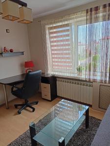 an office with a desk and a chair and a glass table at Apartament Kalia in Zamość