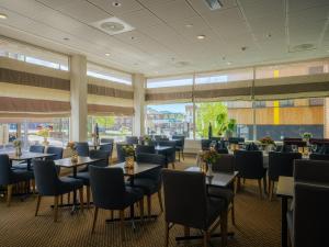 a dining room with tables and chairs and windows at Quality Hotel Grand Steinkjer in Steinkjer