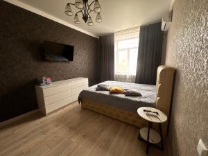 a bedroom with a bed and a tv on the wall at 1 комн.квартира in Balqash