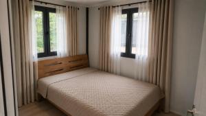 a small bedroom with a bed and two windows at Dīķu oāze in Atspuki