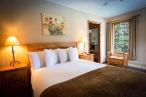 Un dormitorio con una gran cama blanca y una ventana en Paradise Lodge and Bungalows, en Lago Louise