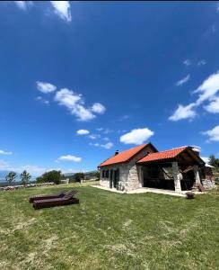 a building with a red roof on a grass field at Košara Trišnjevac in Lusnić