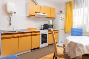 a small kitchen with yellow cabinets and a table and a table at Apartment Bojke in Niš