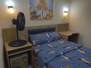 a bedroom with a bed with a blue comforter and a fan at Logos Guest Suites in Ikeja