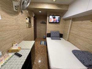 a small room with a bed and a tv on the wall at Sleep Inn in Hong Kong
