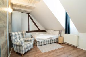 a attic bedroom with a bed and a chair at APLEND Vila Magnolia - Tatry Card v cene in Tatranská Lomnica