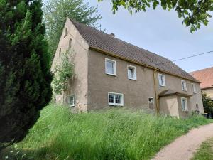 ein altes Haus auf einem grasbewachsenen Hügel neben einer Straße in der Unterkunft Sonnenberghof in Glashütte