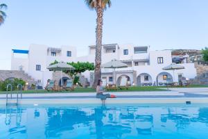 a woman sitting on the edge of a swimming pool at Fragoulis Village in Parasporos