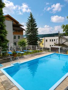 a large blue swimming pool with chairs and a building at Familienhotel Steindl in Millstatt
