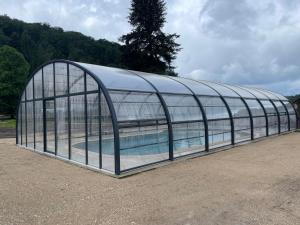 a glass greenhouse with a swimming pool in it at Le clos du Breuchin in Breuchotte