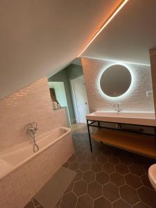 a bathroom with a tub and a sink and a mirror at Le clos du Breuchin in Breuchotte