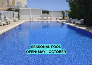 a swimming pool with blue water and white chairs at Seascape 501 in Larnaca