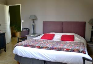 a bedroom with a large bed with two red pillows at Tournefeuille La Cure in Saint-Émilion