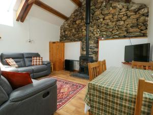 a living room with a couch a table and a fireplace at Bythyn Ddol Hafod in Capel Curig