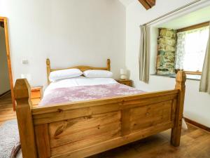 a bedroom with a wooden bed and a window at Bythyn Ddol Hafod in Capel Curig