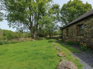a stone house with a grass yard next to a building at Bythyn Ddol Hafod in Capel Curig