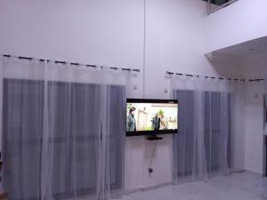 a flat screen tv on a wall with curtains at villa face à la mer in Cotonou