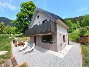 a house with a black roof and a patio at Alpine Daffodil Retreat in Jesenice