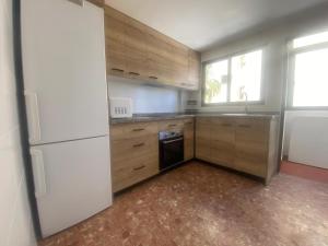 a kitchen with wooden cabinets and a white refrigerator at Maripatri Solo Familias Serviplaya!!! in Playa de Xeraco