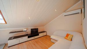 a living room with a white couch and a tv at Apartman Mario with pool by Villas Guide in Blato