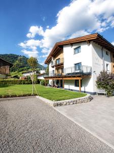 a large white building with a balcony and a yard at das Alpenblick & Outdoor Lodge Nauders in Nauders