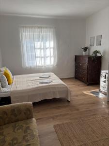 a bedroom with a bed and a dresser and a window at Tornácos Vendégház in Szécsény
