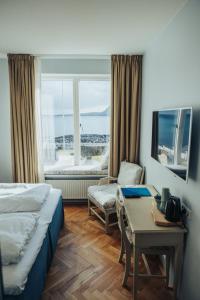 a hotel room with a bed and a desk and a window at Havgrim Seaside Hotel 1948 in Tórshavn