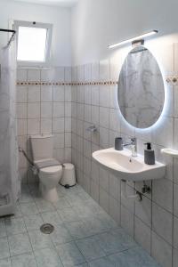 a bathroom with a toilet and a sink and a mirror at Oceanica k rooms in Loutsa