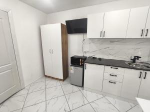 a kitchen with white cabinets and a sink and a refrigerator at Rassvet in Lenīnogorsk