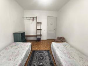 a room with two beds and a door with a shelf at Rassvet in Lenīnogorsk +2 photos