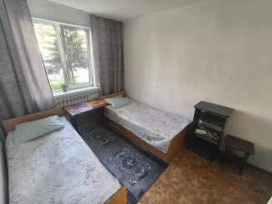 a small room with two beds and a window at Rassvet in Lenīnogorsk