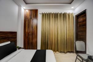 a bedroom with a bed and a curtain and a chair at Townhouse Cloud Bay in Gurgaon +37 photos